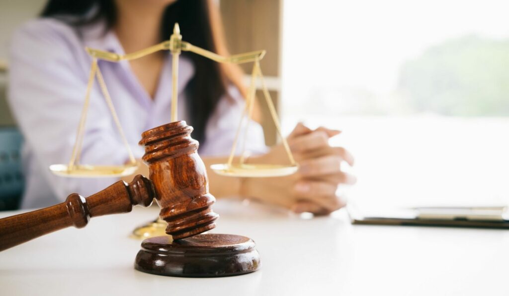 Scales of Justice, Gavel, and a person sitting at a table over legal discussion